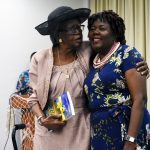 two women hugging and holding a book