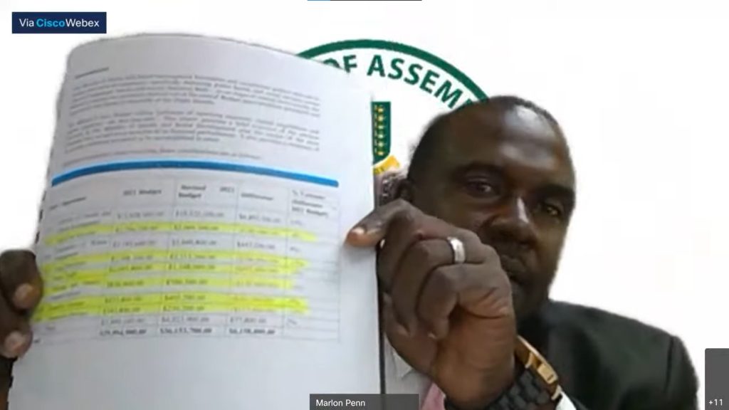 Opposition Leader Marlon Penn holds up a page from the Ministry of Health and Social Development report on budget cuts to social programmes during Tuesday’s debate of the 2022 budget in a virtual House of Assembly sitting. (Screenshot: HOA)